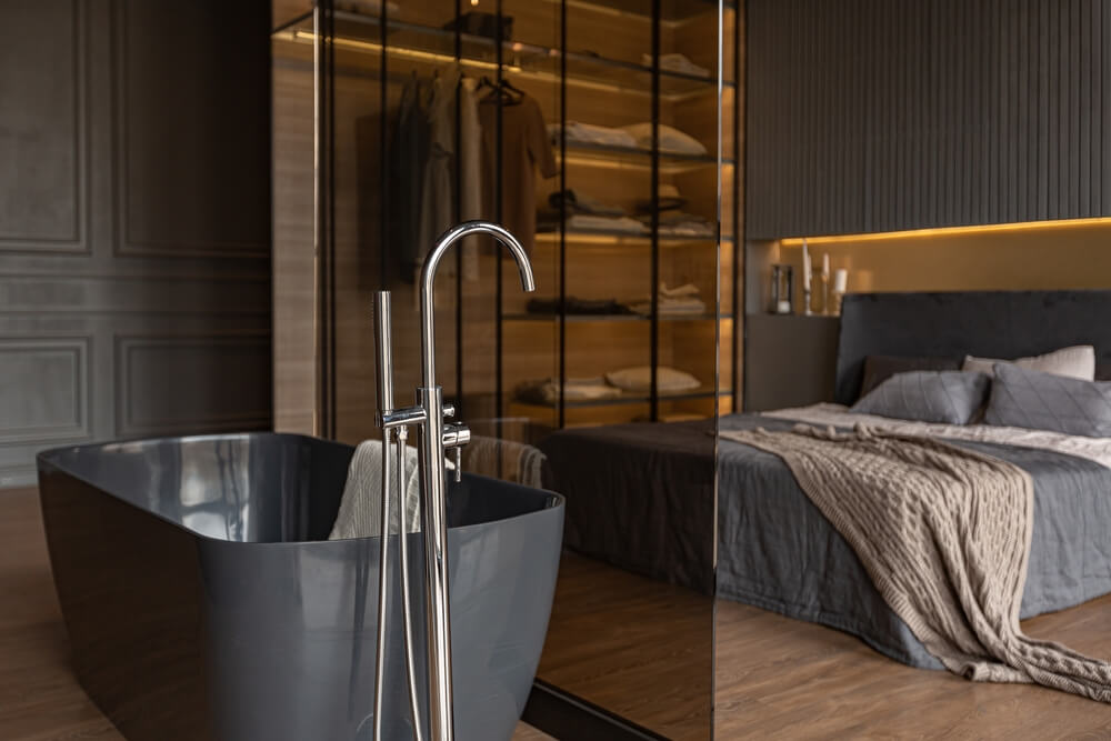 Hotel bedroom and freestanding bath behind a glass partition