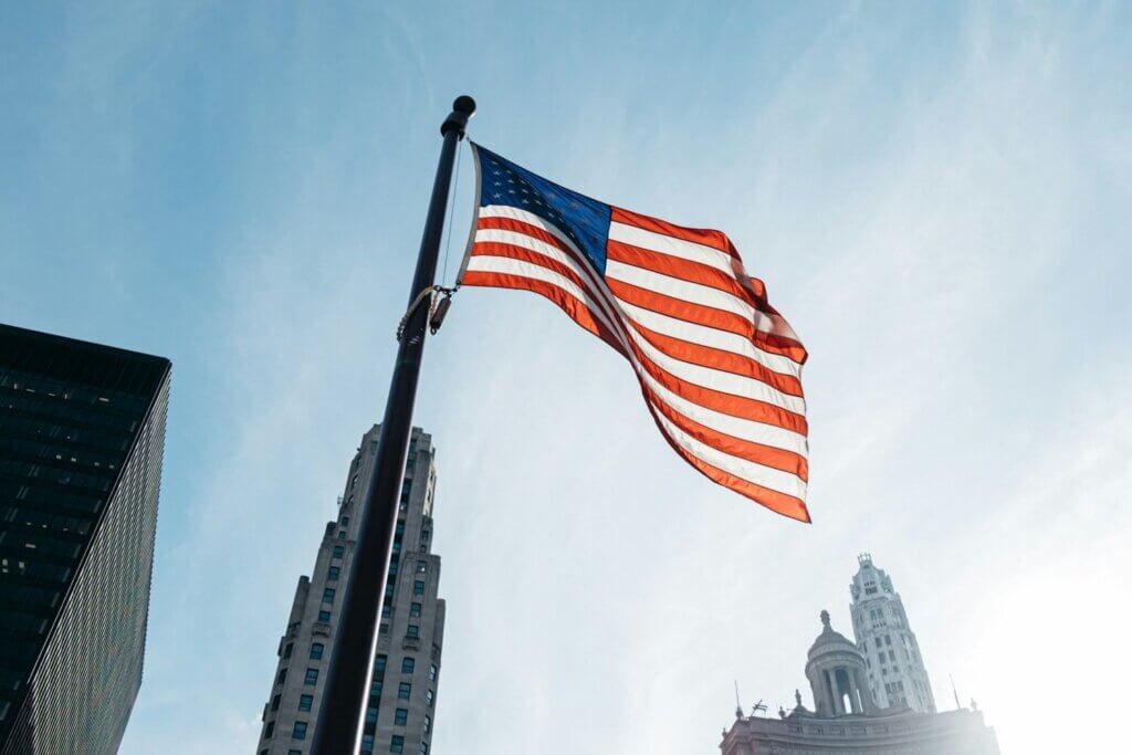 Upward view of US flag in the middle of towering skycraper