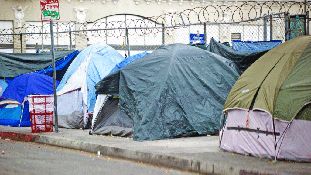 Row of tents on a city sidewalk showing a homeless encampment.