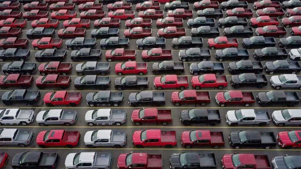 Red and black cars parked in a large outdoor parking lot during daytime