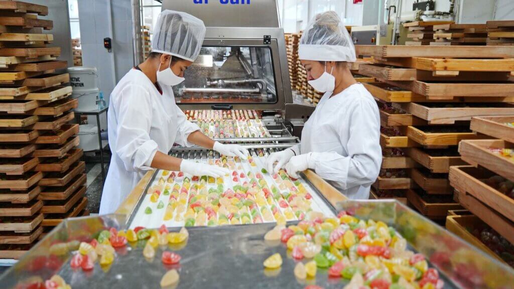 Factory workers sorting marmalade candies on a production line
