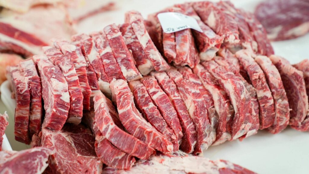 Assorted slices of raw meat neatly arranged on a white tray.