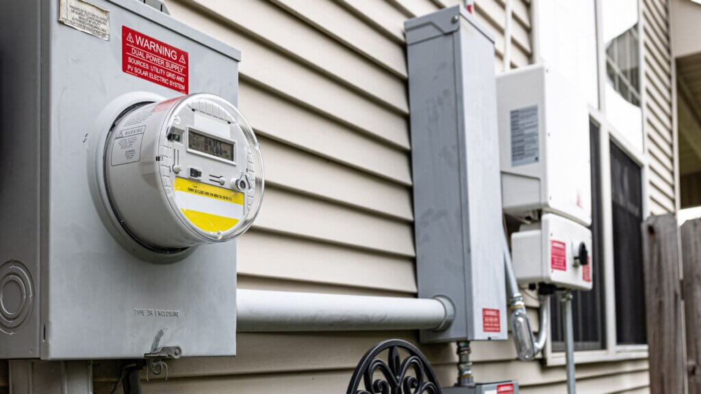 Close up of an electric meter beside a house.