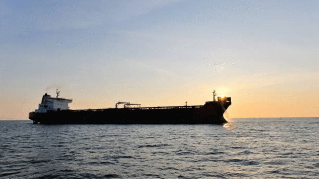 Oil tanker sailing on the ocean at sunset with the sun near the ship’s bow.