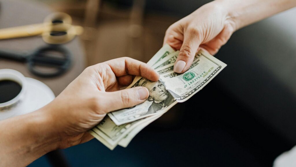 Close-up of hands holding several U.S. dollar bills, symbolizing money, income, or financial transactions