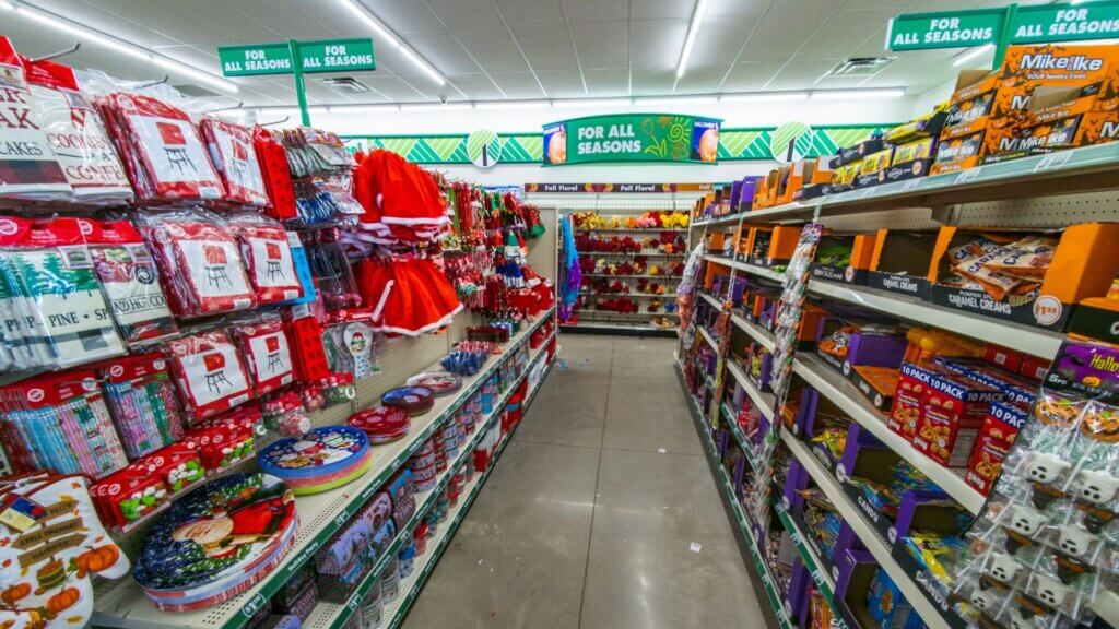 Interior aisle of a Dollar Tree decorated with For All Seasons signage, showing shelves stocked with holiday decor, candy, and seasonal products.