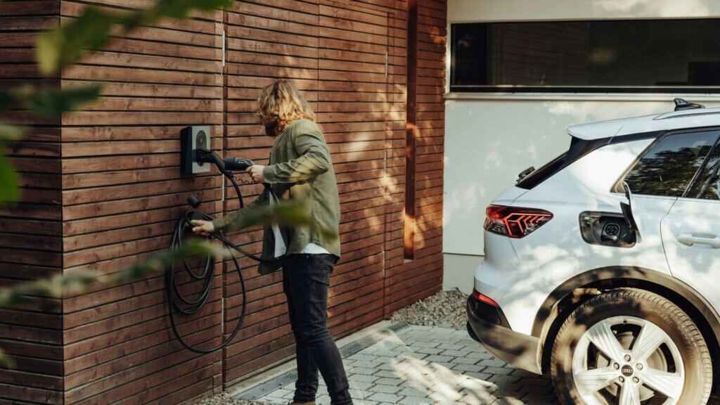 Woman charging her electric car outside her home driveway.