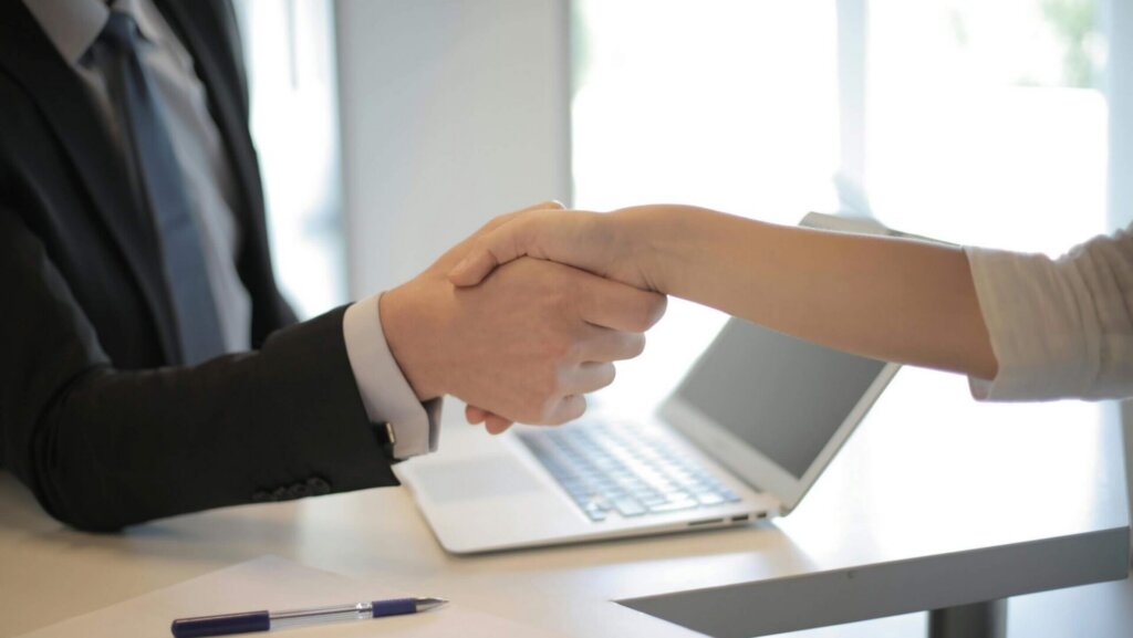 A person in a black suit shaking hands with an employer, representing a successful job hiring or agreement