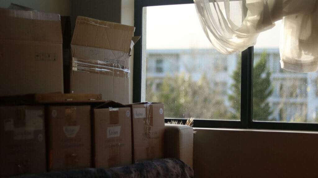 Interior room with packed moving boxes near a window, suggesting relocation