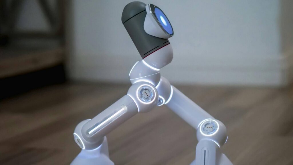 White and gray humanoid robot walking on a wooden surface, captured in motion.