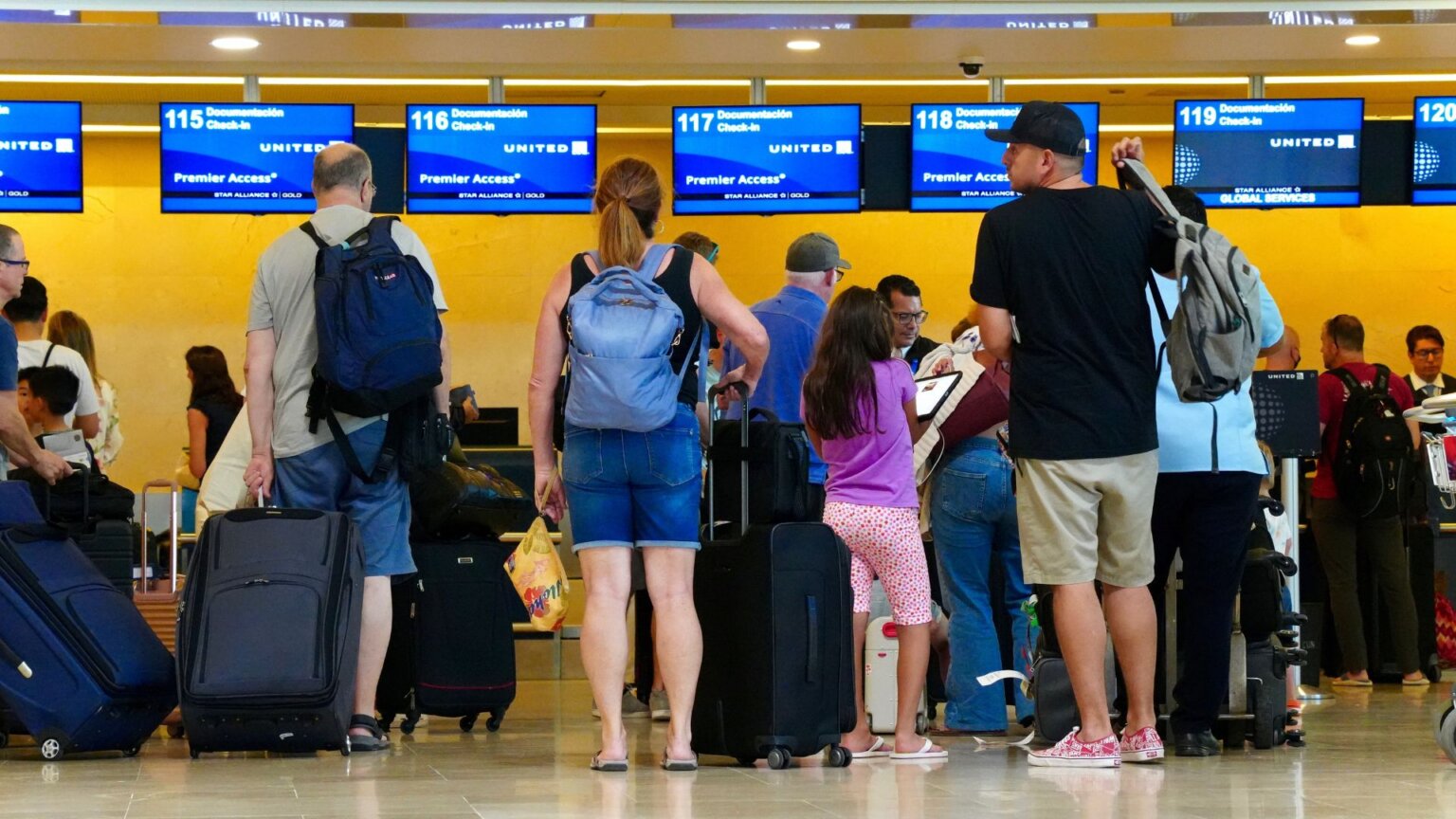 Travelers waiting in line with luggage at an airport check-in counter