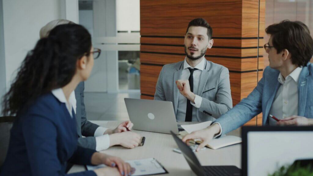 Business professionals meeting around a table with documents and laptops