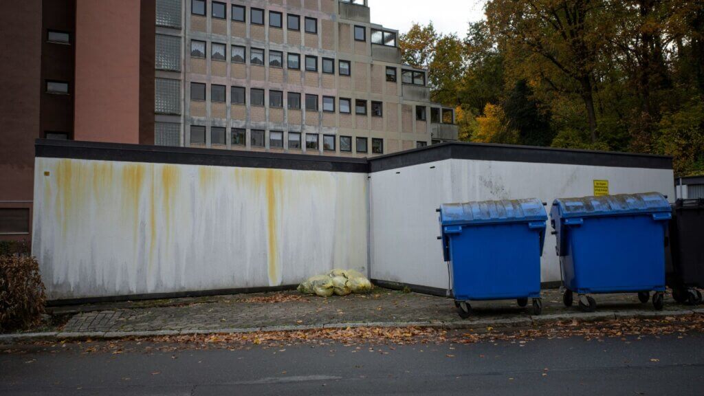 Two blue dumpsters positioned next to a building