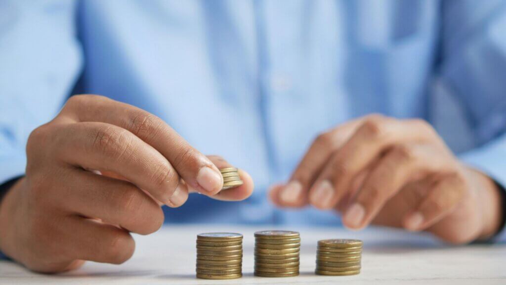 Person stacking coins into small piles on a tabletop