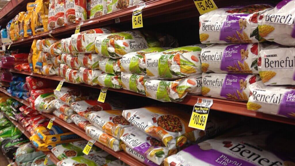 Shelves in a grocery store are stocked with bags of Beneful dog food in colorful packaging.