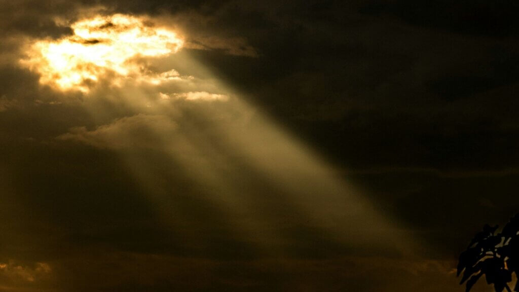 Sunlight breaking through dense clouds in a dramatic sky scene.