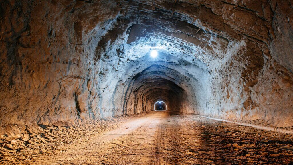 Interior view of an old underground tunnel carved through rock with dim lighting