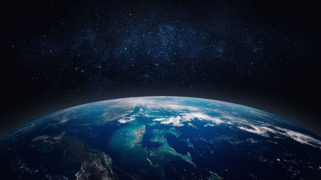 View of Earth from space with stars and sunlight on the horizon