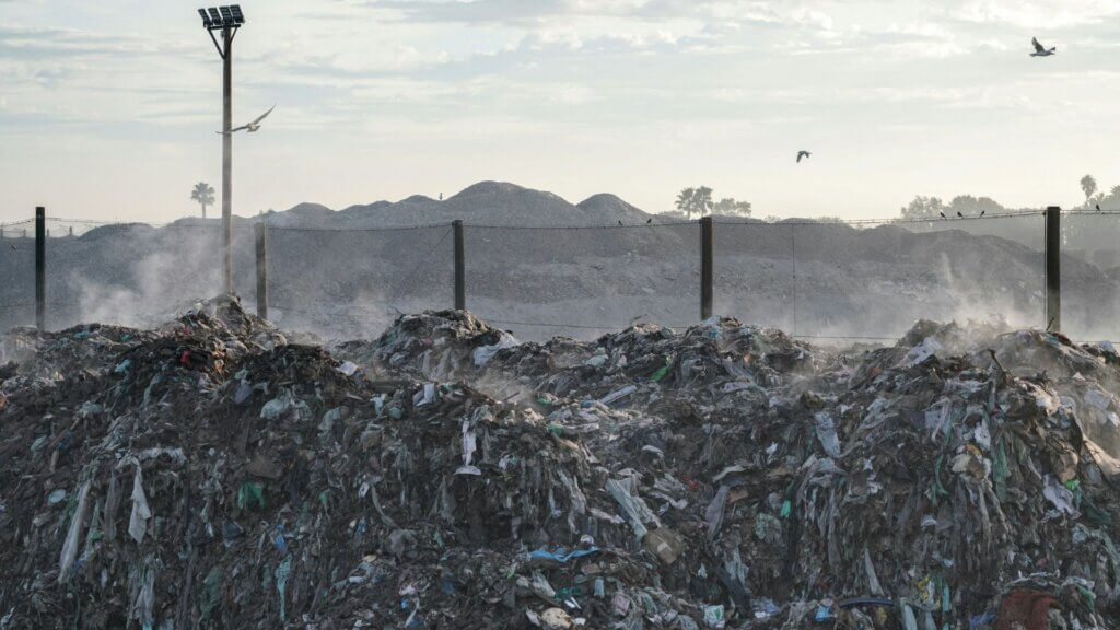 Large pile of garbage near a street light at a landfill