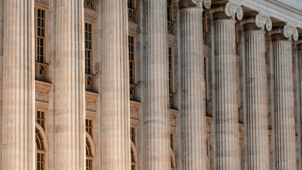 Large government building with columns and a clock on its facade