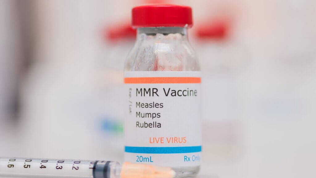 MMR Vaccination vial on counter with syringe in background