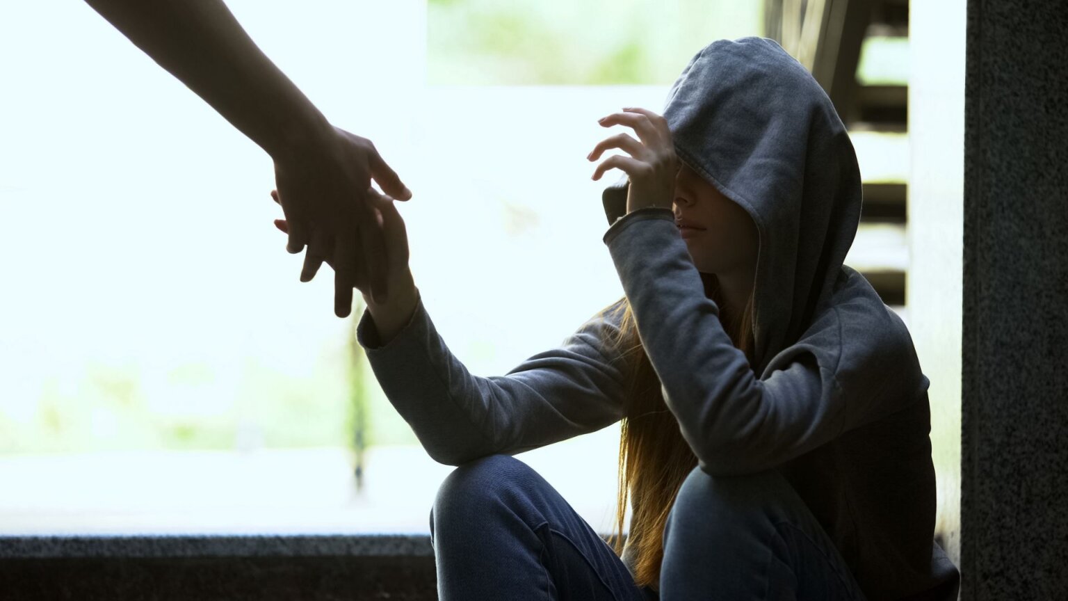 A person stretching a helping hand to a teenager