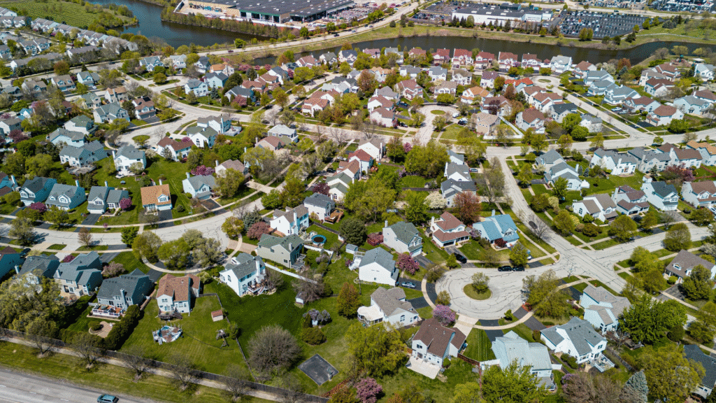Aerial view of a suburban neighborhood with houses, trees, and nearby hills.