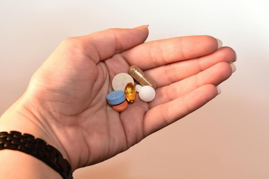 A bunch of supplements on a person's hand.