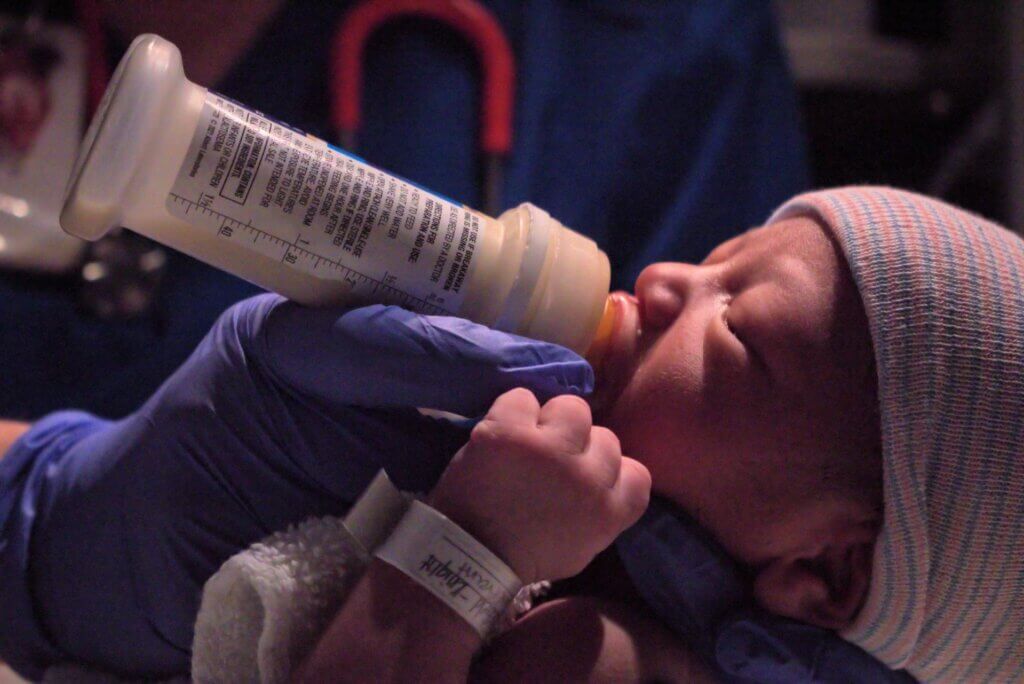 Newborn baby feeding from milk bottle in hospital