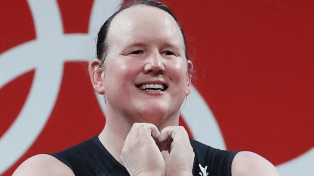 A close-up of New Zealand weightlifter Laurel Hubbard smiling and making a heart gesture.