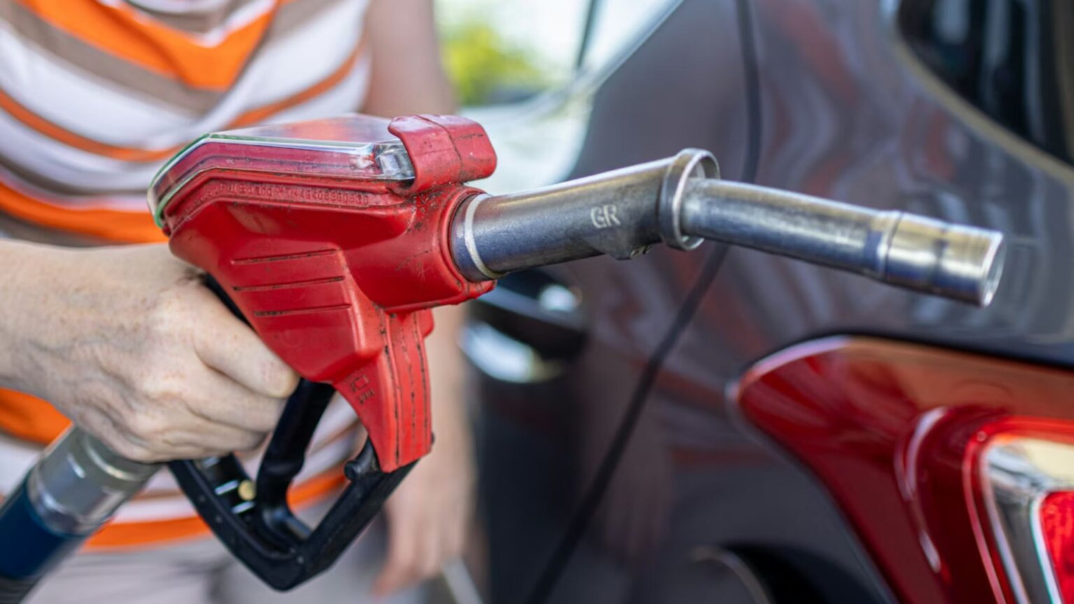 Americans Are Spending $187 Million More a Day on Gas, and Analysts Say It May Hit $4 a Gallon This Month A person holding a red gasoline nozzle about to refuel their car.