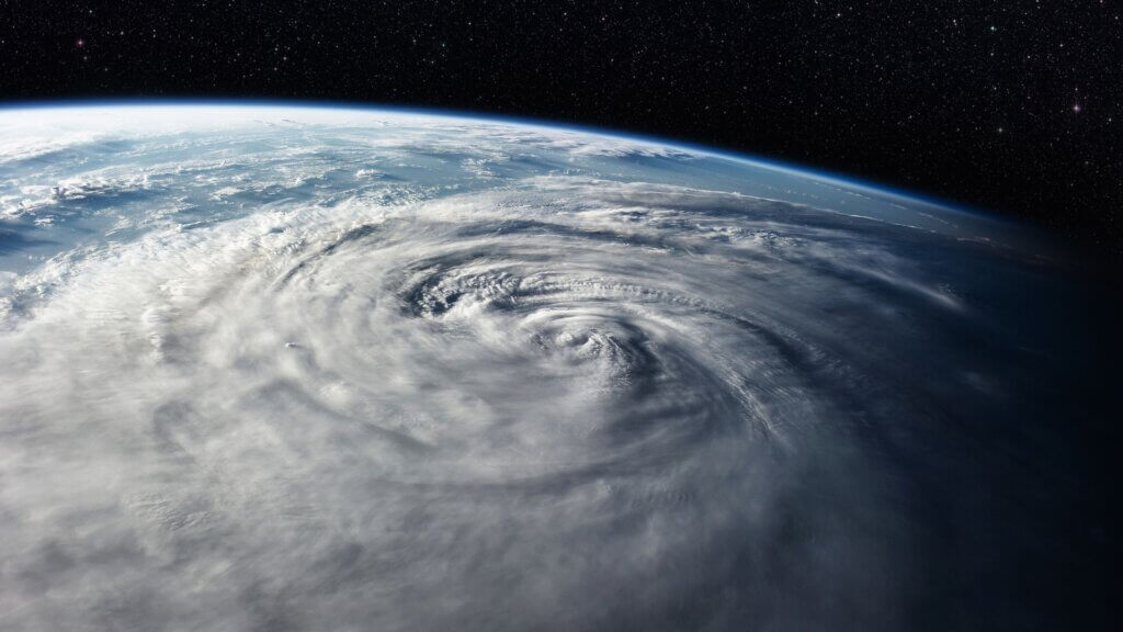 Satellite view of a massive hurricane swirling over Earth above thick cloud bands.