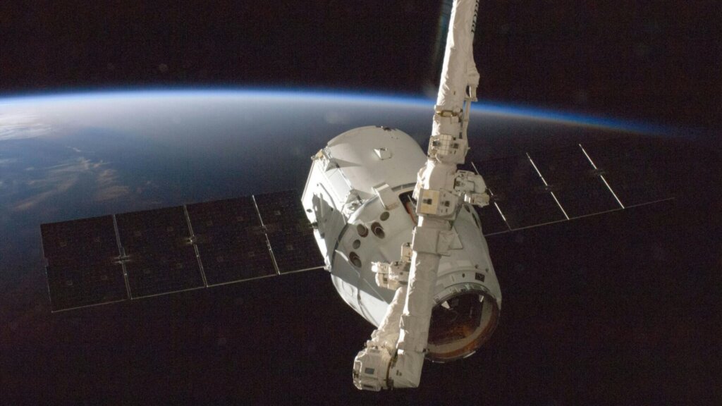 NASA space shuttle Discovery in orbit above Earth with blue atmosphere visible.
