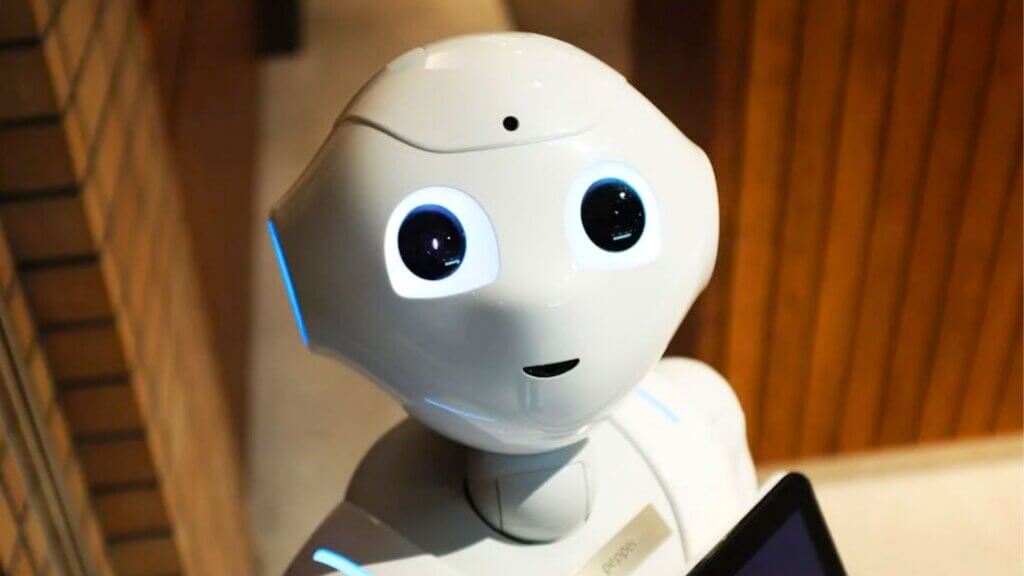 Small humanoid robot with glowing eyes looking up.