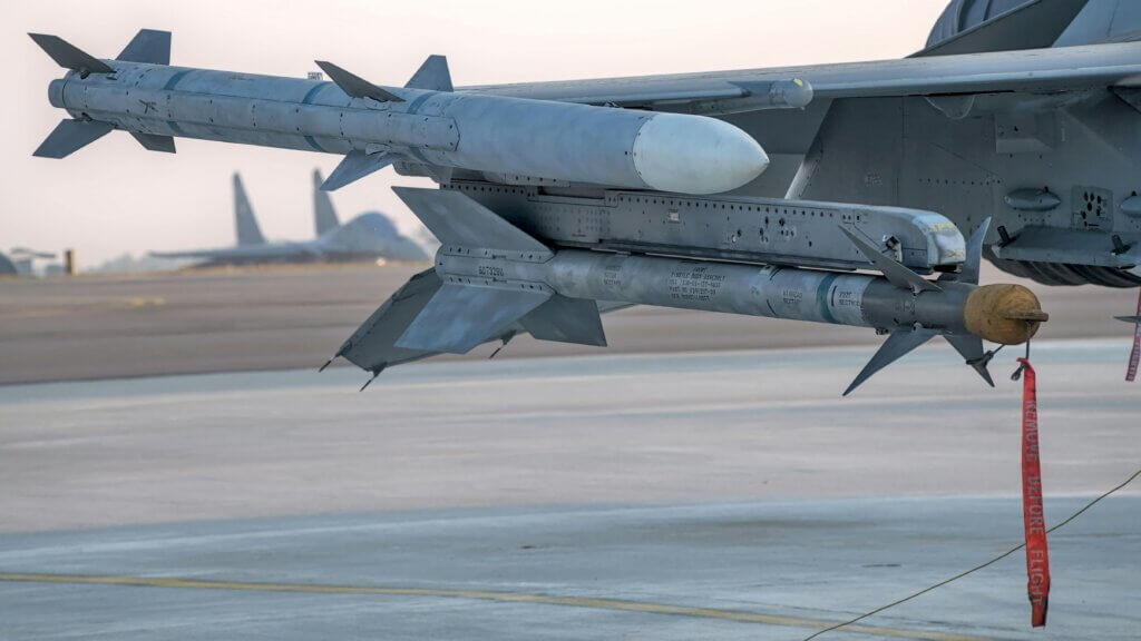 Close-up of a military missile mounted under an aircraft wing.