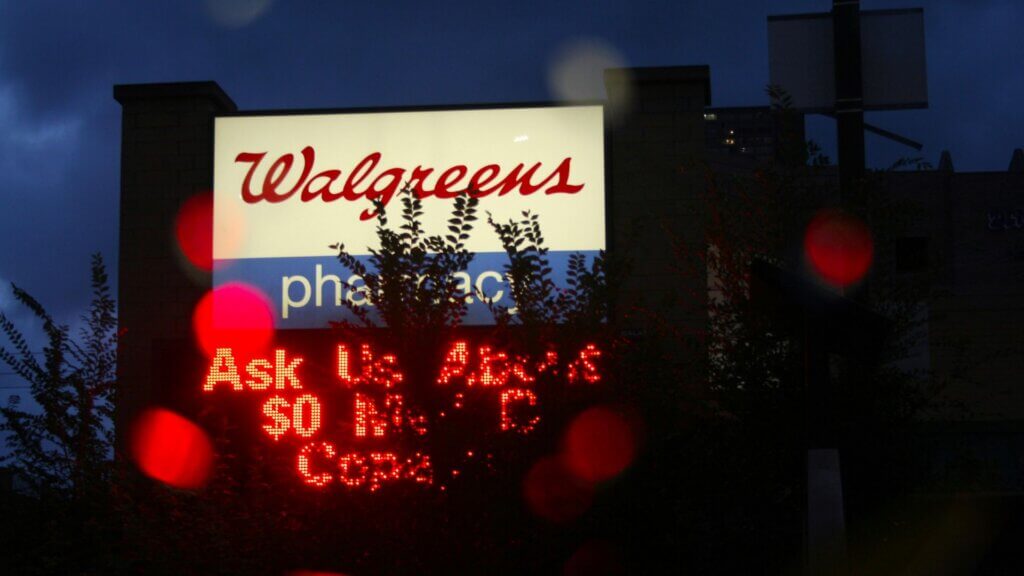 Illuminated Walgreens pharmacy sign at night with a digital message board in front of the store location