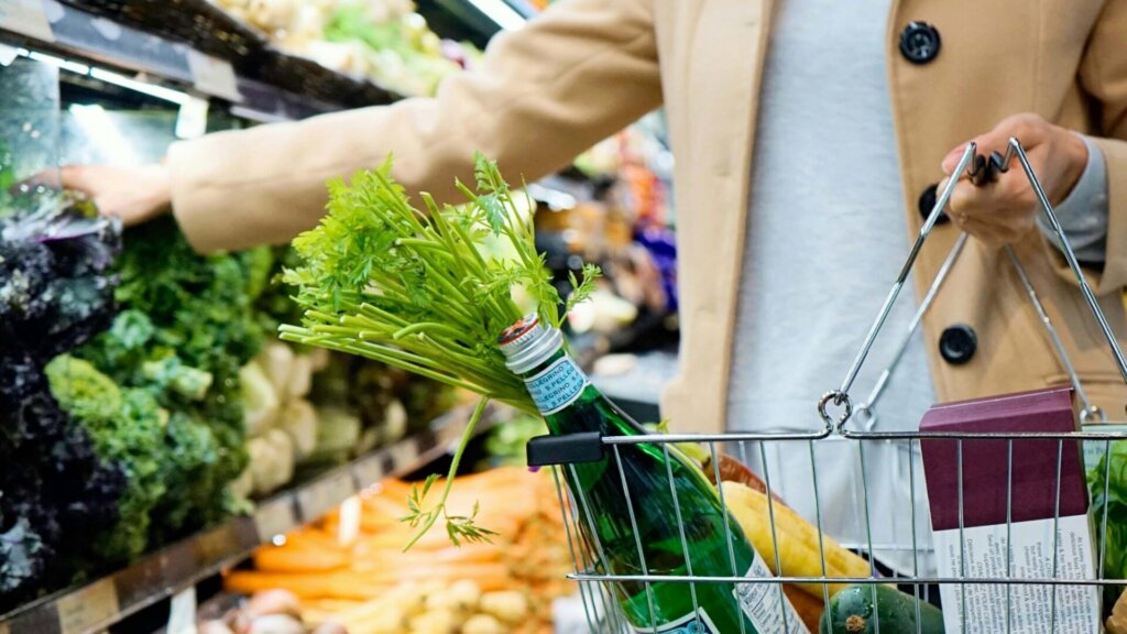 Person holding a shopping basket while browsing in a store.