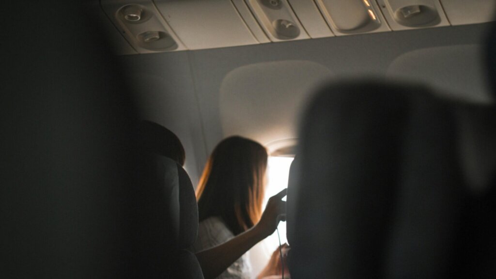 Passenger sitting next to an airplane window watching the view outside.
