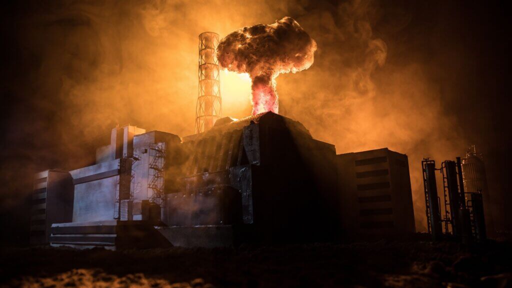 Nuclear reactor facility with glowing explosion and mushroom cloud rising above structure.