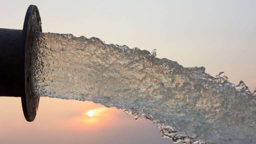 Water rushing from a large pipe at sunset.