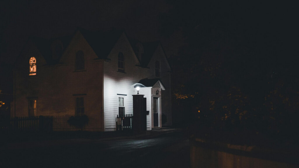 Dimly lit house at night with a porch light illuminating the entrance.