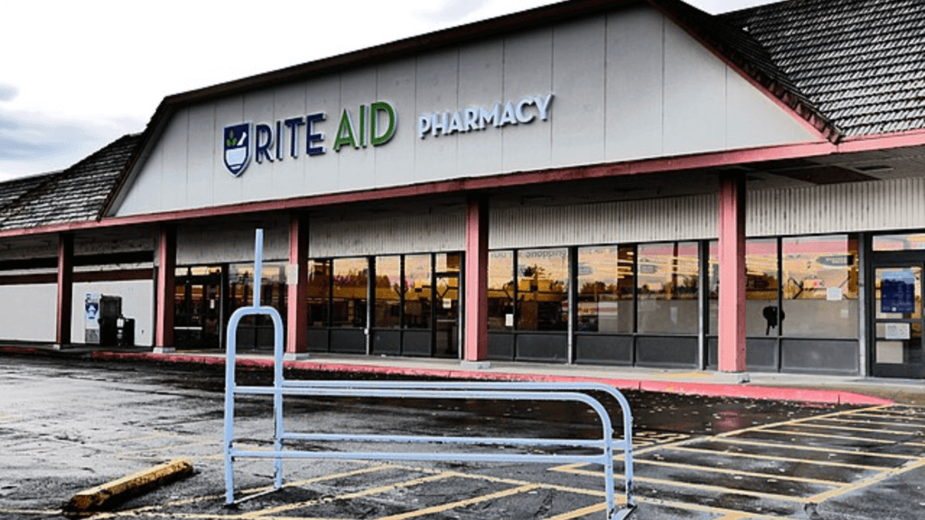 Exterior view of a standalone Rite Aid Pharmacy building with a large parking lot on an overcast day.