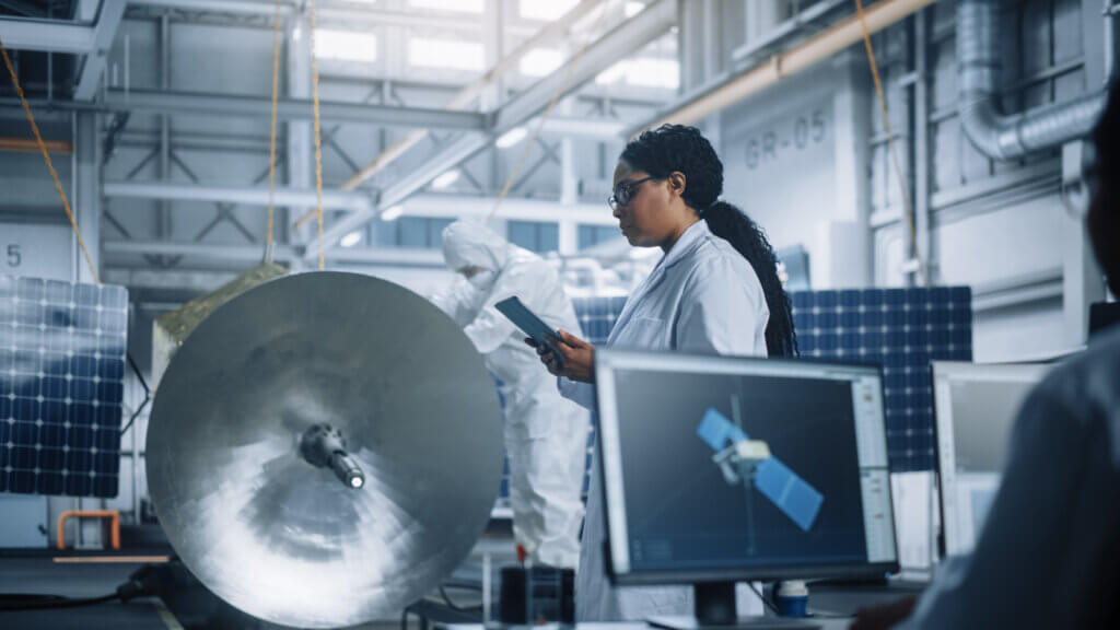 Female engineer using a tablet while working with satellite equipment.