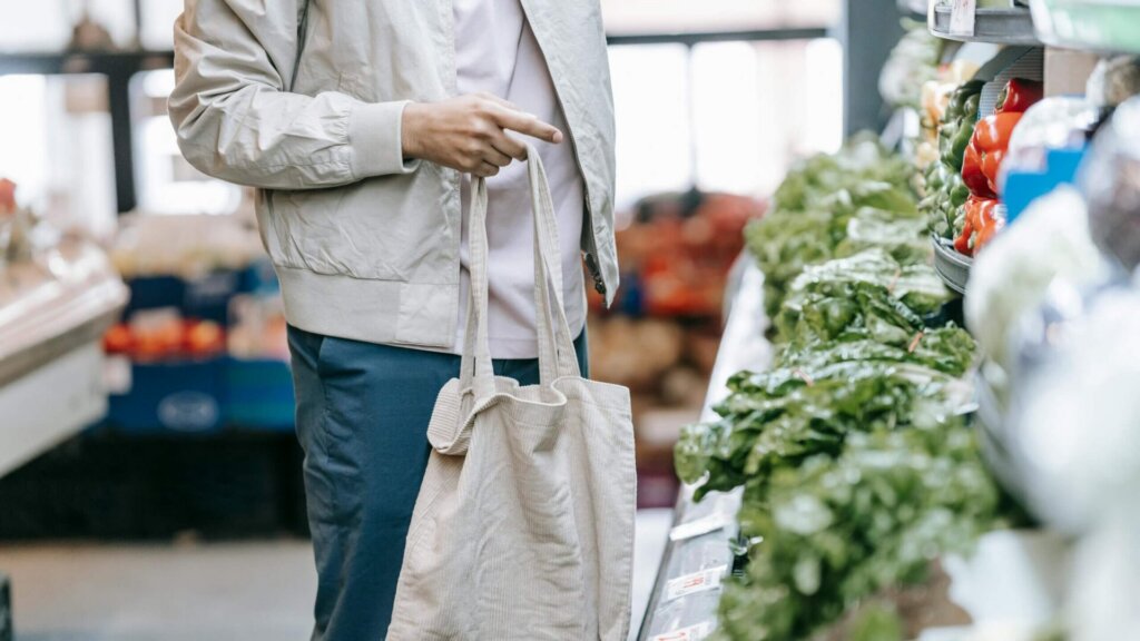 Customer selecting fresh produce in a supermarket aisle.