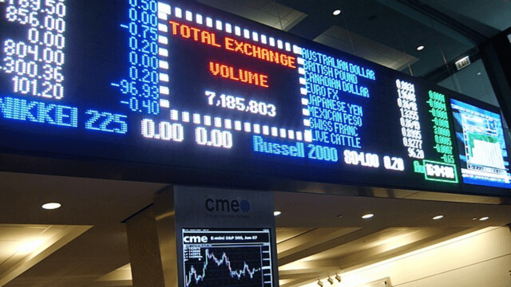 Large electronic display boards at a financial exchange showing real-time market data, currency values, and trading volume.