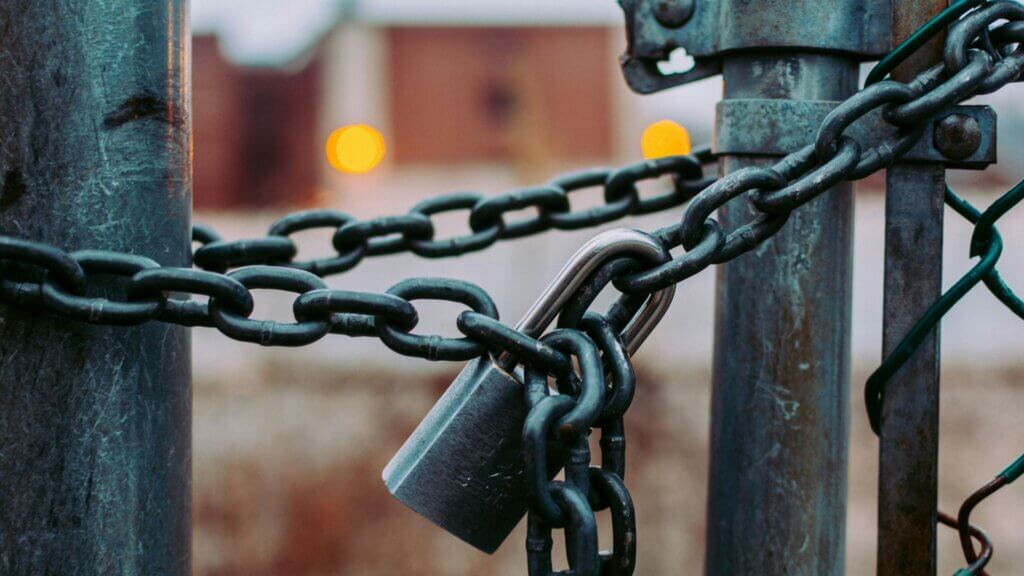Metal chain and padlock securing a gate symbolizing store closures and restricted access