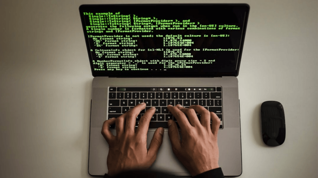 Person typing code on a laptop keyboard.