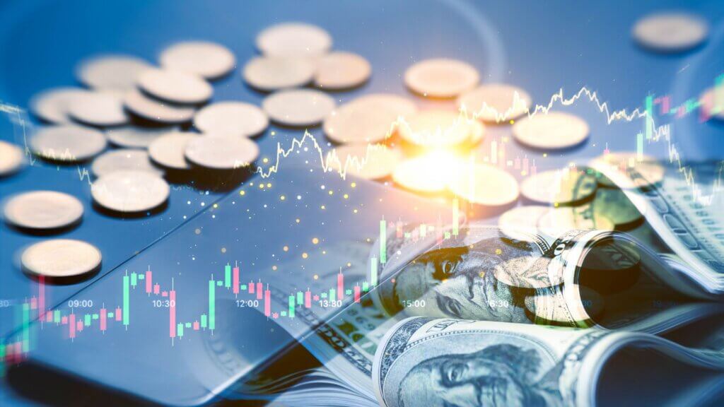U.S. dollar bills and coins with stock market charts and rising financial graphs layered over the image