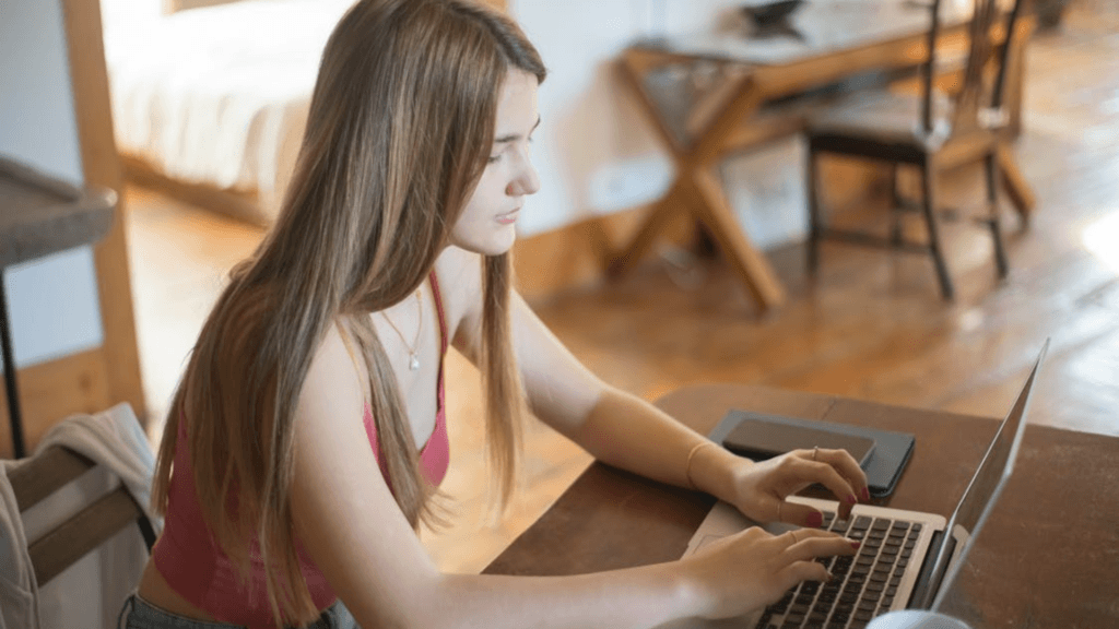 Young woman typing on a laptop at a table.