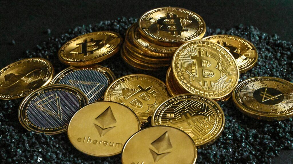Collection of cryptocurrency coins including Bitcoin and Ethereum stacked together on a dark textured surface